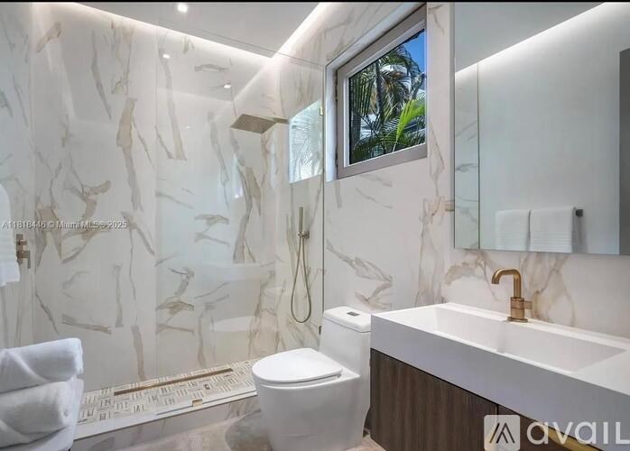 A bathroom with a marble wall and a window showing a tree.
