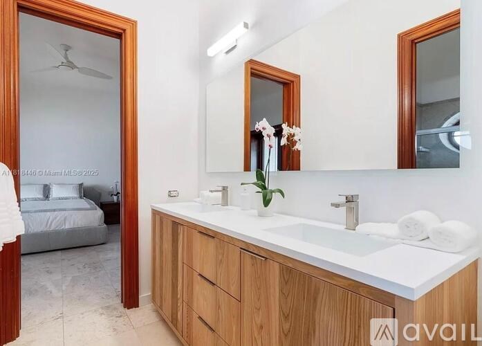 A bathroom with a white countertop and a bedroom in the background.