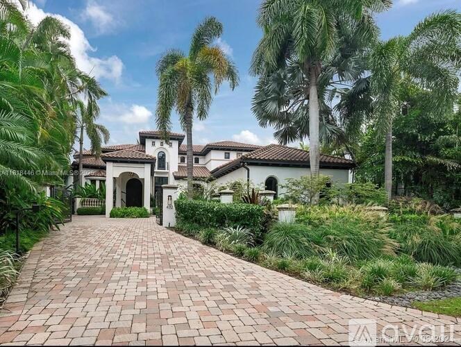 A house with a driveway and palm trees in front.