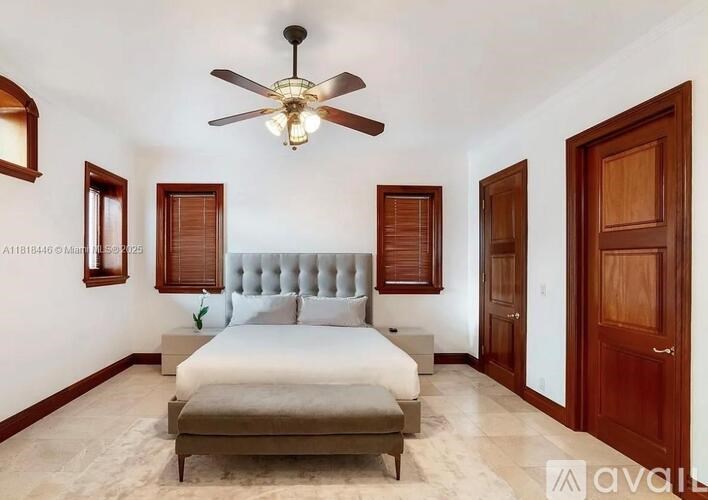A bedroom with a bed, a ceiling fan, and wooden doors.