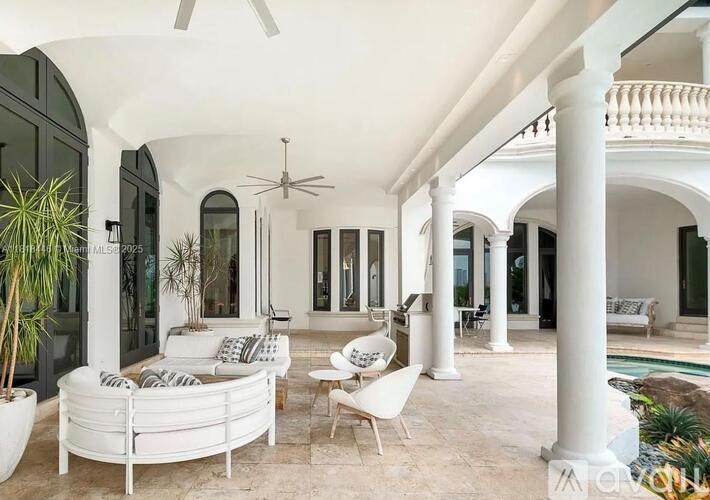 A white outdoor patio with a round white couch and a ceiling fan.