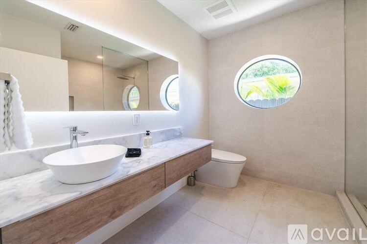 A bathroom with a round window and a white sink.