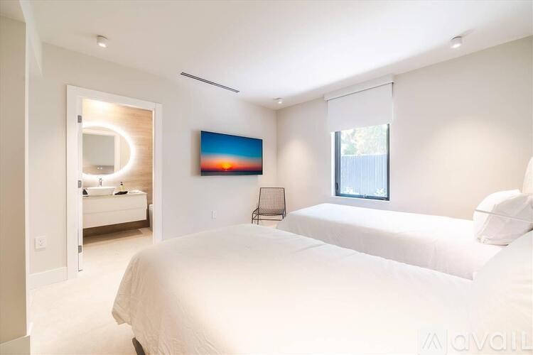 A bedroom with a large bed, a chair, and a painting on the wall.