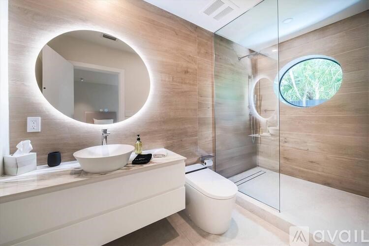 A modern bathroom with a round mirror and a glass shower stall.
