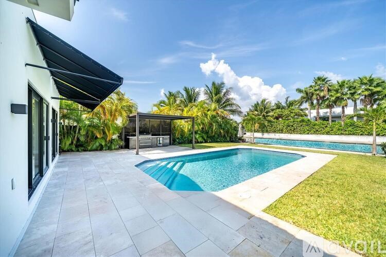 A pool surrounded by a white building and palm trees.