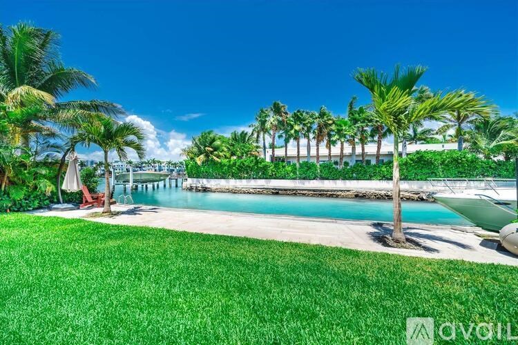 A beautiful outdoor scene with a pool, palm trees, and a clear blue sky.