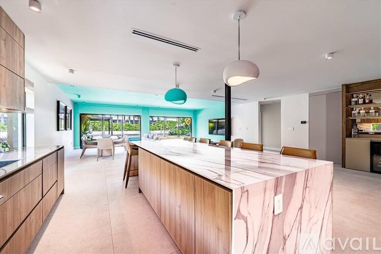 A modern kitchen with a long counter and pendant lights.