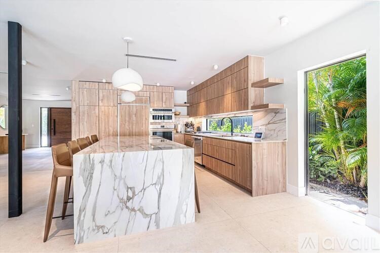 A modern kitchen with a marble island and wooden cabinets.