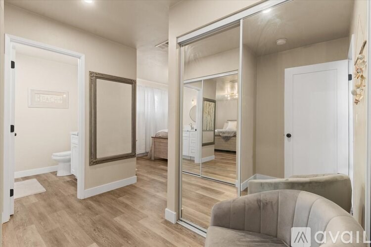 A bedroom with a large mirror and a grey couch.