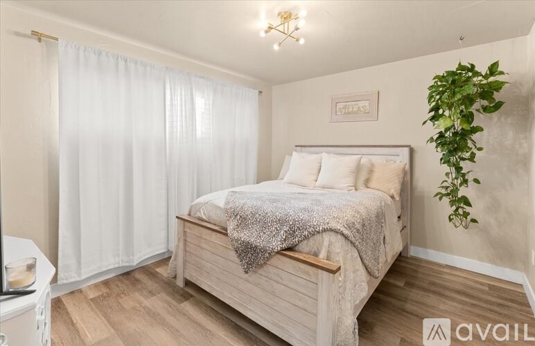 A bedroom with a bed, a nightstand, and a plant.