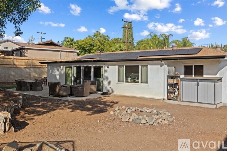 A house with a brown roof and a white wall is shown with a clear blue sky in the background.