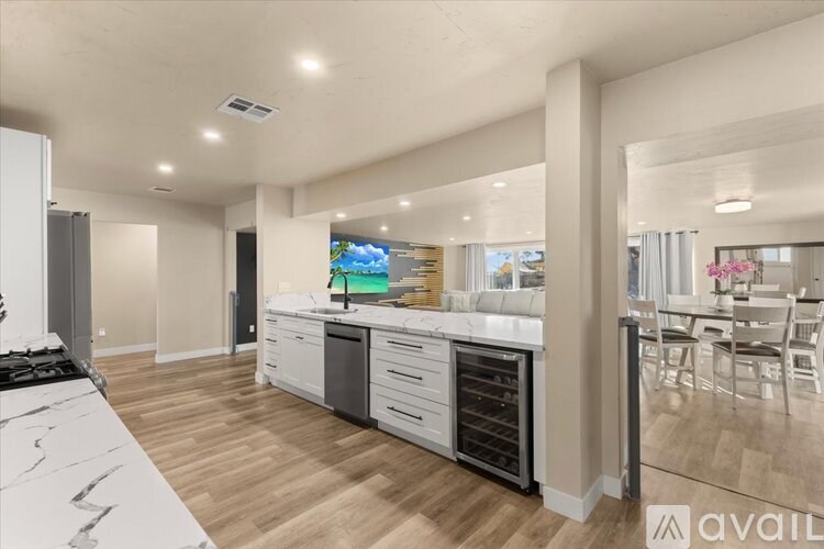 A modern kitchen with a white countertop and wooden flooring.