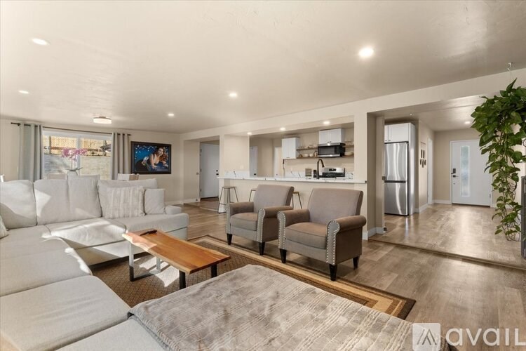 A living room with a white sofa set and a wooden coffee table.
