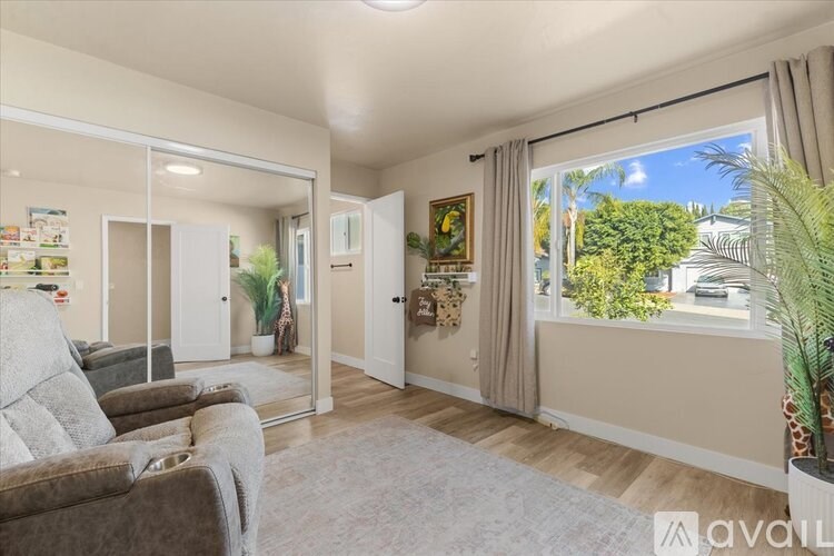 A living room with a couch, a chair, and a large window with a view of the outside.