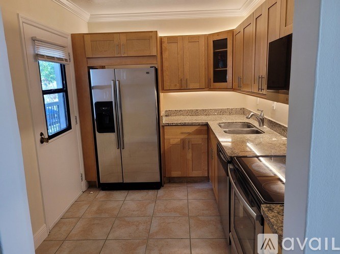 A kitchen with a refrigerator, sink, and cabinets.