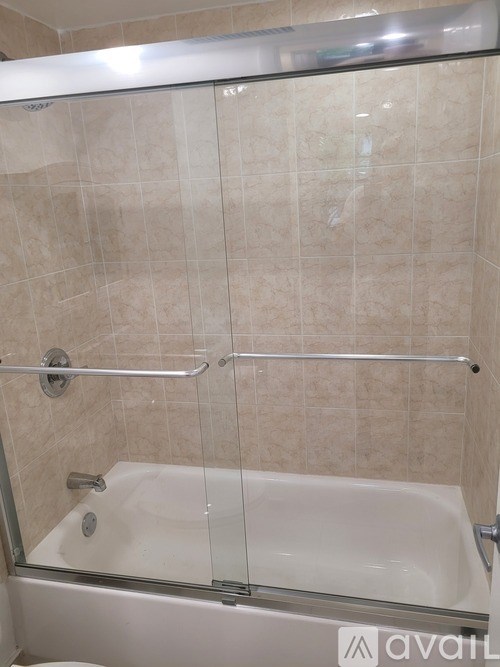 A bathroom with a beige tiled shower and a glass door.