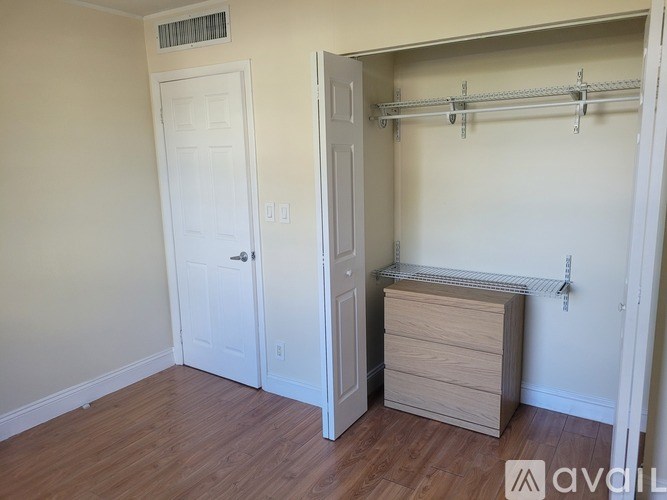 A room with a white door, a white wall, a white closet with a shelf and a white drawer.