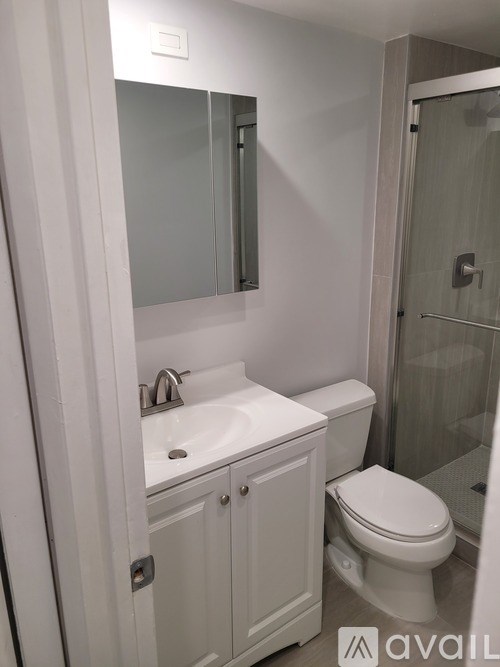 A white bathroom with a toilet, sink, and mirror.