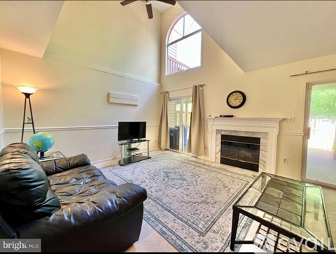 A living room with a black leather couch and a fireplace.