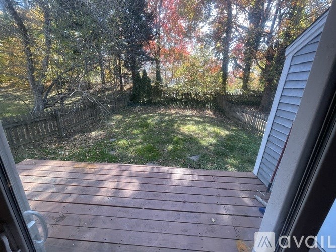 A wooden deck overlooks a backyard with a fence and trees.