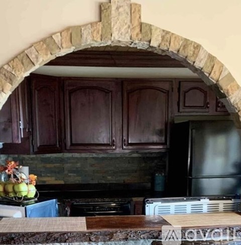 A kitchen with a stone archway and wooden cabinets.