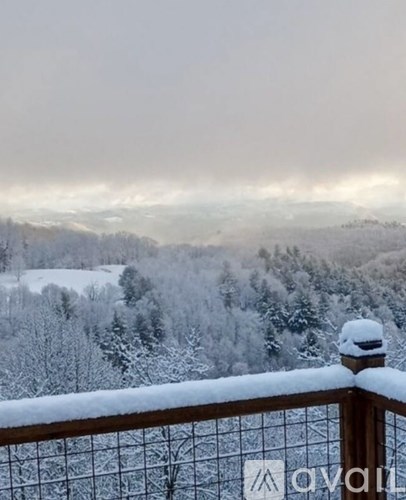 A snowy landscape with a wooden railing in the foreground.