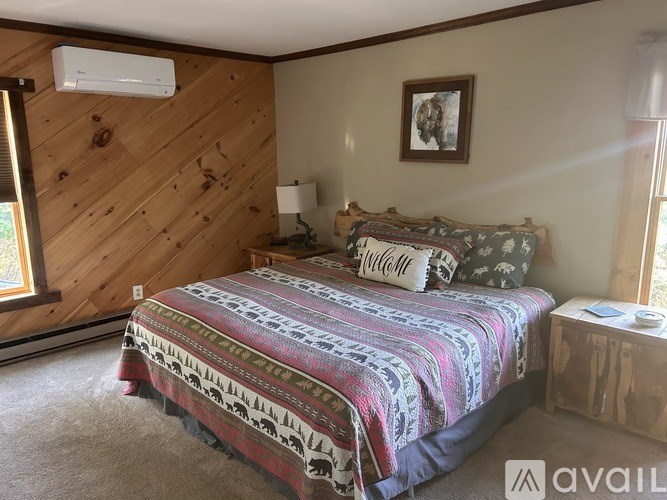 A bedroom with a bed, a lamp, and a picture on the wall.