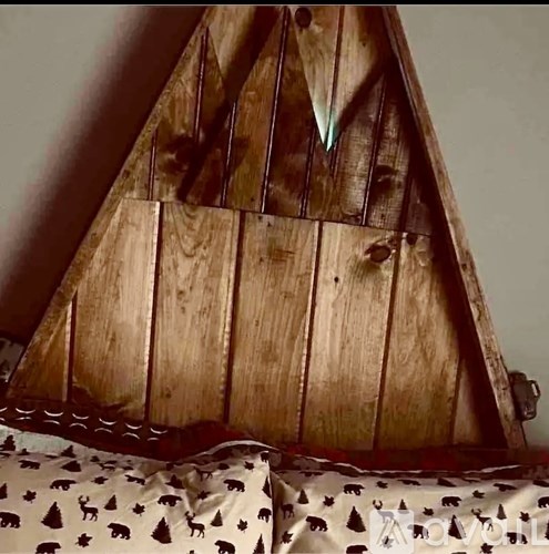 A wooden sailboat model is placed on a fabric with a bear pattern.