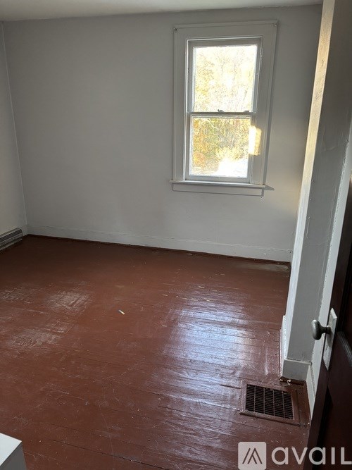 A room with a window and a brown floor.