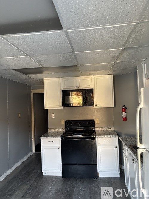 A kitchen with a black stove top oven and white cabinets.