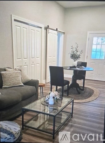 A living room with a glass coffee table and a grey couch.