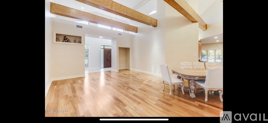 A spacious room with wooden floors and a dining table set up with chairs.