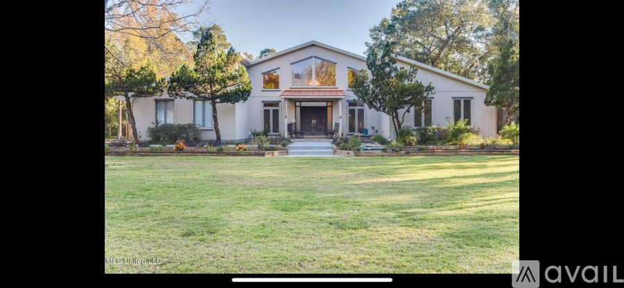 A house with a front yard and a tree in front of it.