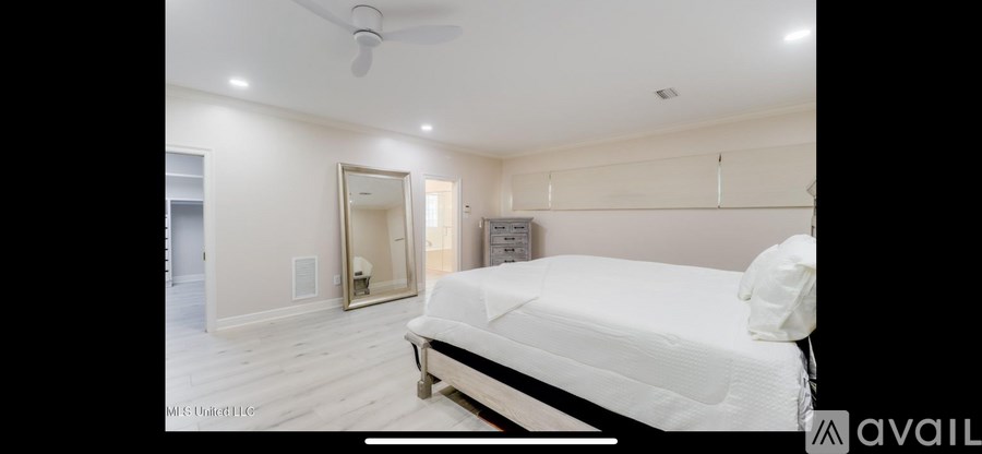 A bedroom with a large bed and a mirror on the wall.