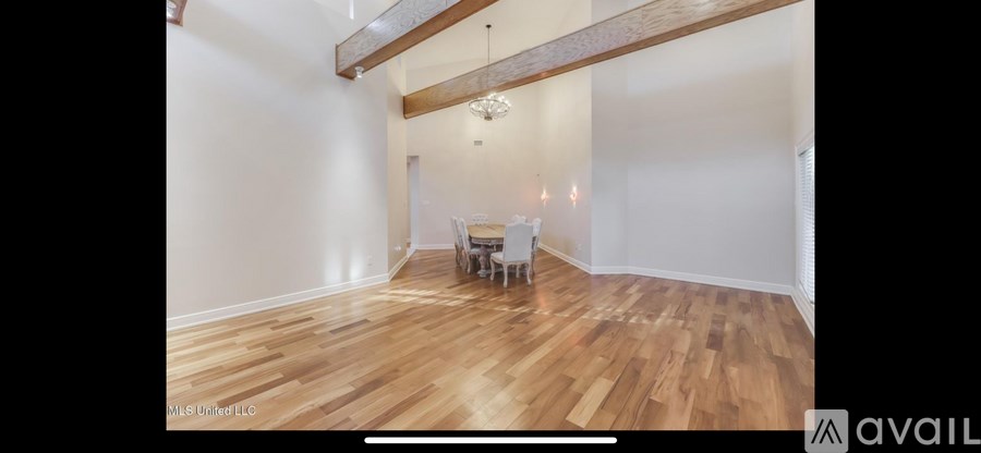 A room with wooden floors and a dining table set up.