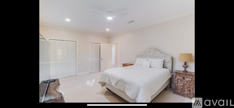 A bedroom with a large bed and a wooden dresser.