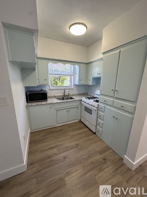 A kitchen with wooden floors and light blue cabinets.