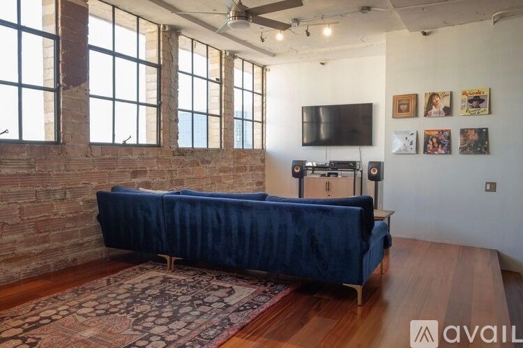 A blue sofa in a room with a brick wall and a flat screen TV.