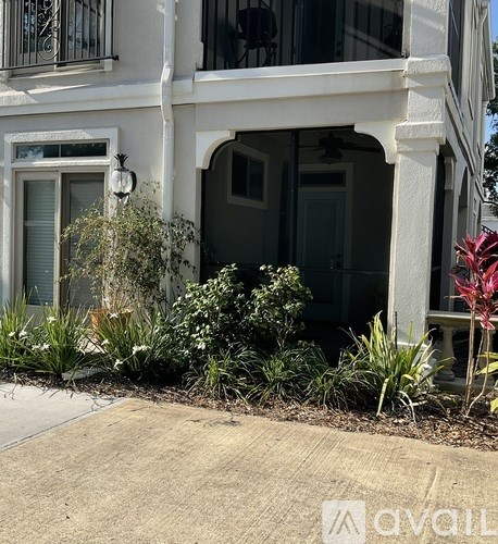 A white building with a balcony and a garden in front.
