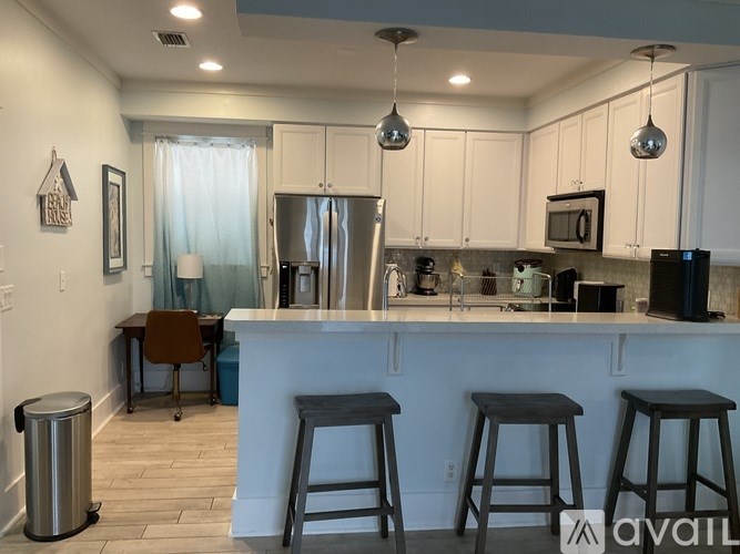 A kitchen with white cabinets and a bar area with stools.