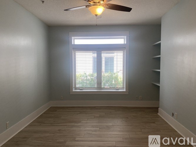 A room with a ceiling fan and a window with blinds.