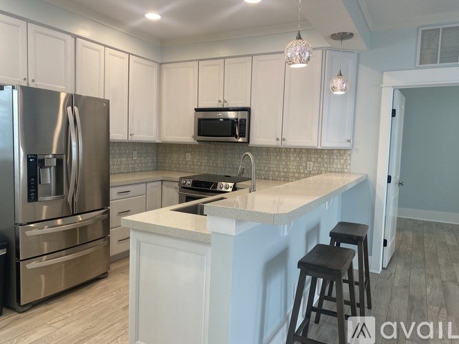 A kitchen with white cabinets and a stainless steel refrigerator.