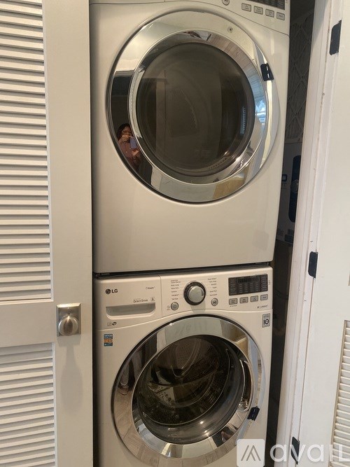 A white washing machine with the door open is in front of a white door.