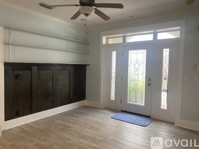 A room with a ceiling fan and a door with a glass panel.