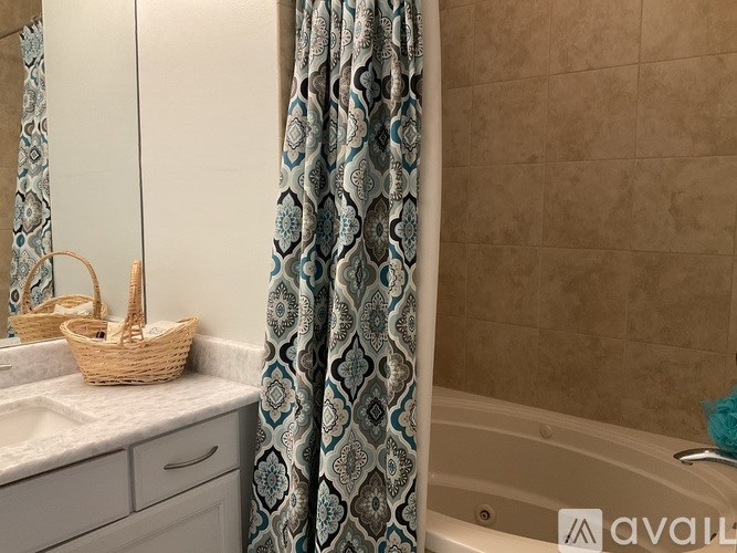 A bathroom with a patterned shower curtain and a basket on the sink.