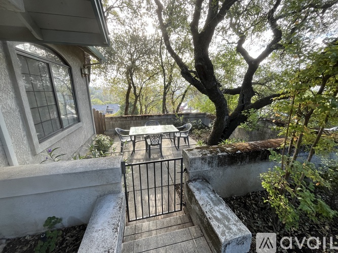 A patio with a table and chairs is surrounded by a fence and trees.