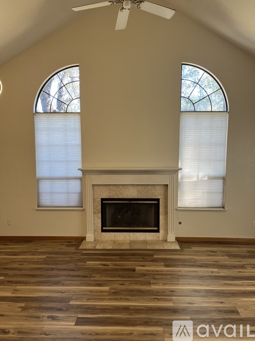 A living room with a fireplace and two windows.