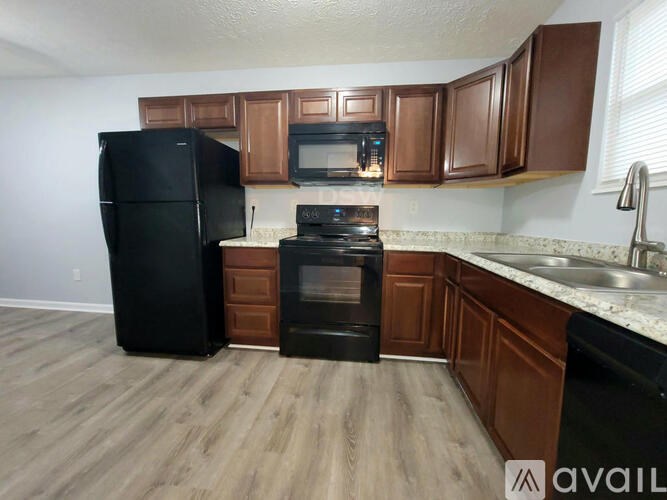 A kitchen with black appliances and brown cabinets.