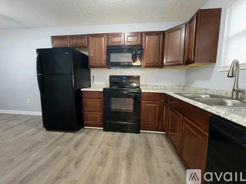 A kitchen with black appliances and brown cabinets.