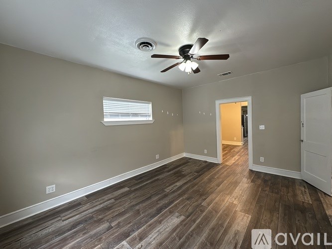 A room with a ceiling fan and wooden flooring.